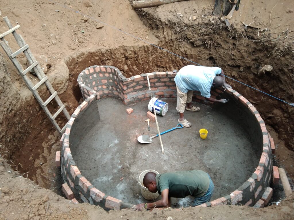 the brick dome being plastered from the inside Local builders plastering the interior of a biogas digester dome in Machame